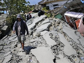 A man walks on a heavily damaged street due to the earthquake in Balaroa neighborhood in Palu, Central Sulawesi, Indonesia Indonesia, Tuesday, Oct. 2, 2018. Desperation was visible everywhere Tuesday among victims receiving little aid in areas heavily damaged by a massive earthquake and tsunami, four days after the disaster devastated parts of Indonesia's central Sulawesi island.