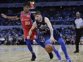 Luka Doncic of the Dallas Mavericks, right, controls the ball past Markelle Fultz of the Philadelphia 76ers, during the Shenzhen basketball match between the Philadelphia 76ers and the Dallas Maverick, part of the NBA China Games, in Shenzhen city, south China's Guangdong province, Monday, Oct. 8, 2018.