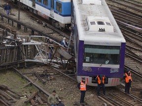 FILE - In this Aug. 6, 2012 file photo, police officers stand in front of a derailed commuter train at the downtown Retiro station in Buenos Aires, Argentina. A court in Argentina has sentenced on Wednesday, Oct. 10, 2018, the former planning minister Julio De Vido for his role in the 2012 train accident that left more than 50 people dead and hundreds injured.