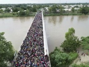 This frame grab from video provided by Televisa, shows migrants bound for the U.S.-Mexico border waiting on a bridge that stretches over the Suchiate River, connecting Guatemala and Mexico, in Tecun Uman, Guatemala, Friday, Oct. 19, 2018.  The gated entry into Mexico via the bridge has been closed. The U.S. president has made it clear to Mexico that he is monitoring its response. On Thursday he threatened to close the U.S. border if Mexico didn't stop the caravan. (Televisa via AP)