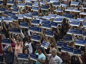 People hold street signs honoring slain councilwoman Marielle Franco as they mark the 7th month since her murder in Rio de Janeiro, Brazil, Sunday, Oct. 14, 2018. Franco supporters distributed a thousand street signs in memory of her after a video on social media showed one being destroyed by two politicians with the right wing Social Liberal Party.