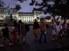 Honduran migrants walk past the National Palace as they leave Guatemala City at sunrise Thursday, Oct. 18, 2018 as they make continue their way north toward the U.S.  Many of the more than 2,000 Hondurans in a migrant caravan trying to wend its way to the United States left spontaneously with little more than the clothes on their backs and what they could quickly throw into backpacks.