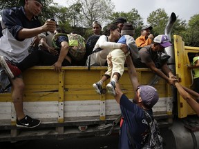 Honduran migrants bound to the U.S border climb into the bed of a truck in Zacapa, Guatemala, Wednesday, Oct. 17, 2018. The group of some 2,000 Honduran migrants hit the road in Guatemala again Wednesday, hoping to reach the United States despite President Donald Trump's threat to cut off aid to Central American countries that don't stop them.