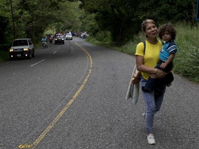 Honduran migrant Mary Dominguez, 27, carries her two-year-old son Dominic during a caravan of hundreds of Honduras migrants making their way to the U.S., as the group leaves Esquipulas, Guatemala, Tuesday, Oct. 16, 2018. U.S. President Donald Trump threatened on Tuesday to cut aid to Honduras if it doesn't stop the impromptu caravan of migrants, but it remains unclear if governments in the region can summon the political will to physically halt the determined border-crossers.