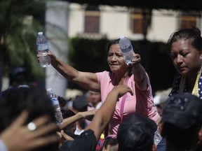 Residents hand out water bottles to Central American migrants making their way to the U.S. in a large caravan, at the main plaza in Tapachula, Mexico, Monday, Oct. 22, 2018.  Thousands of Central American migrants hoping to reach the U.S. were deciding Monday whether to rest in this southern Mexico town or resume their arduous walk through Mexico as President Donald Trump rained more threats on their governments.
