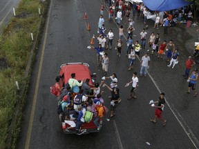 Mexicans from religious organizations hand out small bags containing water, toilet paper, diapers and medicine to Central American migrants who got a free ride from a motorist, in Xochiltepec, Mexico, Monday, Oct. 22, 2018. Motorists in pickups and other vehicles have been offering the Central American migrants rides, often in overloaded truck beds, as the group of about 7,000 people heads to the U.S. border.