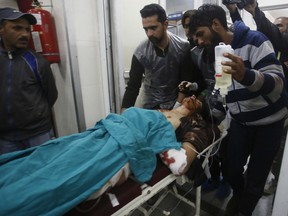 Kashmiri men take an injured civilian on a stretcher inside a hospital in Srinagar, Indian controlled Kashmir, Sunday, Oct. 21, 2018. Three suspected rebels were killed in a gun battle with Indian government forces in disputed Kashmir on Sunday, and at least three civilians were killed in an explosion at the site after the fighting was over, officials and residents said.