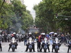 Police go after demonstrators who where throwing stones at them outside Argentina's Congress where lawmakers are discussing next year's budget in, Buenos Aires, Argentina Wednesday, Oct. 24, 2018. The budget includes austerity measures including tax hikes and government cuts aimed at eliminating the fiscal deficit.