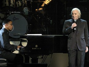 FILE - In this Feb. 6, 2004 file photo, singer Charles Aznavour, right, performs as Herbie Hancock plays piano during the MusiCares 2004 Person of the Year Tribute to Sting, in Culver City, Calif. Charles Aznavour, the French crooner and actor whose performing career spanned eight decades, has died. He was 94.