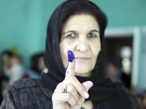 An Afghan woman shows her inked finger after casting her vote at a polling station during the Parliamentary elections in Kabul, Afghanistan, Saturday, Oct. 20, 2018. Tens of thousands of Afghan forces fanned out across the country as voting began Saturday in the elections that followed a campaign marred by relentless violence.