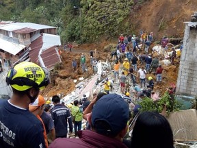 In this handout photo released by the Caldas Department Press Office, rescue workers attend to the wreckage of a house destroyed by a landslide in Marquetalia, Colombia, Thursday, Oct. 11, 2018. At least 12 people were killed in a landslide triggered by heavy rains in a neighborhood of the municipality of Marquetalia in northwest Colombia, said the National Unit for Disaster Risk Management. (Caldas Department Press Office via AP)