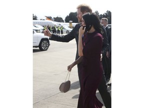 Britain's Prince Harry, left, and his wife, Meghan, the Duchess of Sussex, wave as they prepare to depart at the airport following the Invictus Games in Sydney, Sunday, Oct. 28, 2018. Prince Harry and Meghan are traveling to New Zealand to continue their tour of the South Pacific.