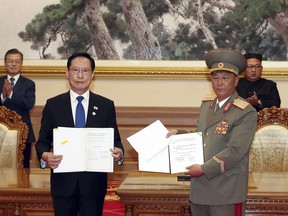 FILE - In this Sept. 19, 2018, file photo, South Korea's Defense Minister Song Young-moo, front left, and North Korea's Minister of the People's Armed Forces No Kwang Chol, front right, hold the documents after signing as South Korean President Moon Jae-in, rear left, and North Korean leader Kim Jong Un, rear right, clap at the Paekhwawon State Guesthouse in Pyongyang, North Korea. North and South Korea began removing mines at two sites inside their heavily fortified border Monday, Oct. 1,  as part of their recent deals to ease decades-long military tensions.(Pyongyang Press Corps Pool via AP, File)