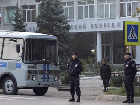 Policemen stand guard near a vocational college in Kerch, Crimea, Thursday, Oct. 18, 2018. An 18-year-old student strode into his vocational school in Crimea, a hoodie covering his blond hair, then pulled out a shotgun and opened fire on Wednesday, killing scores of students and wounding dozens of others before killing himself. (AP Photo)