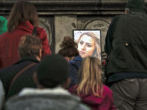 A portrait of slain television reporter Viktoria Marinova is placed on the Liberty Monument, as people wait to place flowers and candles during a vigil in Ruse, Bulgaria, Monday, Oct. 8, 2018. Bulgarian police are investigating the rape, beating and slaying of a female television reporter whose body was dumped near the Danube River after she reported on the possible misuse of European Union funds in Bulgaria. Authorities discovered the body of 30-year-old Viktoria Marinova on Saturday in the northern town of Ruse near the Romanian border. One Bulgarian media site demanded an EU investigation, fearing that Bulgarian officials were complicit in the corruption.