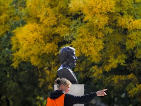 A municipal worker gestures next to the bust of Nobel laureate Elie Wiesel in Bucharest, Romania, Tuesday, Oct. 9, 2018. A bust of Romanian-born writer Elie Wiesel has been unveiled in Bucharest on the country's national Holocaust remembrance day. The director of Romania's National Institute for the Study of the Holocaust joined Bucharest's mayor and the U.S. and Israeli ambassadors on Tuesday for the event in a small square named after Wiesel in the capital.