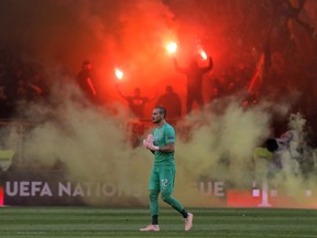 Serbia's goalkeeper Predrag Rajkovic walks on the pitch as Romanian fans light flares during the UEFA Nations League soccer match between Romania and Serbia on the National Arena stadium in Bucharest, Romania, Sunday, Oct. 14, 2018.