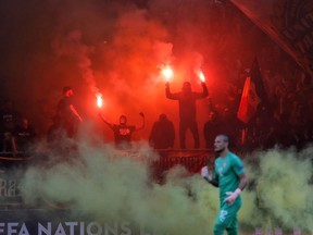 Serbia's goalkeeper Predrag Rajkovic walks on the pitch as Romanian fans light flares during the UEFA Nations League soccer match between Romania and Serbia on the National Arena stadium in Bucharest, Romania, Sunday, Oct. 14, 2018.