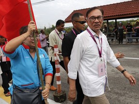 Malaysian politician Anwar Ibrahim, right, visits a polling station in the southern coastal town of Port Dickson, where Anwar is vying for a seat along with six other candidates, Saturday, Oct. 13, 2018. Voting opened Saturday in a by-election that is expected to see charismatic Malaysian politician Anwar Ibrahim win a parliamentary seat and return to active politics as he prepare for his eventual takeover from Prime Minister Mahathir Mohamad.