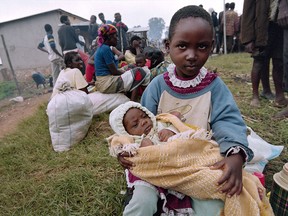 A young girl, fleeing the war-ravaged Rwandan capital of Kigali with her father, holds her sister on the roadside on May 27, 1994. Their mother went missing in the fighting in Kigali and was believed to be dead. Some 400,000 Rwandans were fleeing south of Kigali following the advance of the Tutsi-dominated Rwandan Patriotic Front.