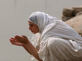 In this Sunday, Oct. 14, 2018 photo, a follower of the obscure and ancient Mandaean faith performs rituals along a strip of embankment on the Tigris River reserved for them, in Baghdad, Iraq. Every Sunday worshippers bathe themselves in the waters to purify their souls. But unlike in ancient times, the storied river that runs through Baghdad is fouled by the smells of untreated sewage and dead carp, which float by in the fast-moving current.