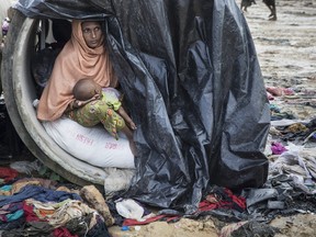 Sameera, 20, looks our from a cement cylinder holding her 7 month old baby where the family are living until a shelter is built September 17, 2017 in Kutupalong, Cox's Bazar, Bangladesh.