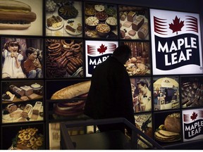 A Maple Leaf Foods employee walks past a Maple Leaf sign at the company's meat facility in Toronto on Monday, December, 15, 2008.