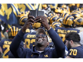 Chris Webber, a former Michigan basketball player, smiles while recording on the sidelines before an NCAA college football game against the Penn State in Ann Arbor, Mich., Saturday, Nov. 3, 2018.