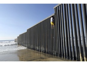 Central American migrant Cristian Andino, 16, from Honduras, gets down from the border structure installed in the Pacific Ocean in Tijuana, Mexico, Friday, Nov. 16, 2018. With about 3,000 Central American migrants having reached the Mexican border across from California and thousands more anticipated, the mayor of Tijuana said Friday that the city was preparing for an influx that will last at least six months and may have no end in sight.