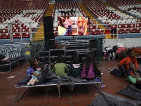 Central American children, part of the caravan hoping to reach the U.S. border, watch TV at the Benito Juarez Auditorium, used as a migrant shelter, in Guadalajara, Mexico, Monday, Nov. 12, 2018. Several thousand Central American migrants marked a month on the road Monday as they hitched rides toward the western Mexico city of Guadalajara.