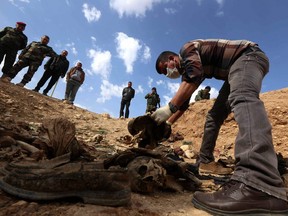 In this file photo taken on Feb. 03, 2015, members of the Yazidi minority search for clues that might lead them to missing relatives in the remains of people killed by ISIL, a day after Kurdish forces discovered a mass grave near the Iraqi village of Sinuni.