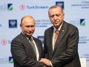 Turkish President Tayyip Erdogan (R) and his Russian counterpart Vladimir Putin shake hands on stage during a ceremony to mark the completion of the sea part of the TurkStream gas pipeline, in Istanbul, on November 19, 2018.
