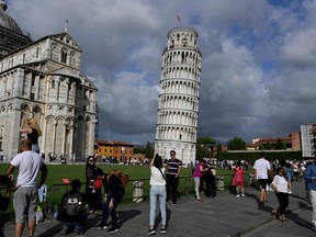 Tourists pose  for photographs at the Pisa tower at the square of Miracles in Pisa.