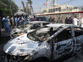 Pakistani security personnel stand next to burned out vehicles in front of the Chinese consulate after an attack in Karachi on November 23, 2018.