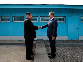 North Korea's leader Kim Jong Un, left, shakes hands with South Korea's President Moon Jae-in  at the Military Demarcation Line that divides their countries ahead of their summit at the truce village of Panmunjom on April 27, 2018.