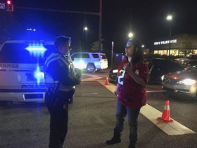 In this Thursday, Nov. 22, 2018 photo, a police officer speaks to a woman after gunfire erupted Thanksgiving night at the Riverchase Galleria in Hoover, Ala. Police responding to a fight inside the shopping mall shot and killed a man who had brandished a weapon, authorities said Friday. Several other people were injured, including a 12-year-old girl.