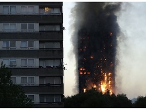 FILE - In this Wednesday, June 14, 2017 file photo smoke and flames rise from the Grenfell Tower high-rise building in west London.  London police have arrested five people over a video that showed a cardboard model of Grenfell Tower being burned on a bonfire. The Metropolitan Police say the men turned themselves in late Monday, Nov. 5, 2018 and were arrested on suspicion of a public order offence after allegedly creating an effigy of the fire-ravaged west London apartment building. The men, ranging in ages from 19 to 55, were taken into custody.