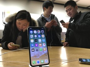 Shoppers check out the iPhone X at an Apple store in Beijing, China. Apple Inc told investors Thursday it will stop providing unit sales for iPhones, iPads, and Macs in fiscal 2019.