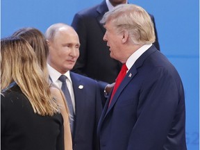 Russia's President Vladimir Putin, left, watches President Donald Trump, right, walk past him as they gather for the group photo at the start of the G20 summit in Buenos Aires, Argentina, Friday, Nov. 30, 2018. Leaders from the Group of 20 industrialized nations are meeting in Buenos Aires for two days starting today.
