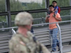 People pass U.S. Army soldiers while crossing from Mexico into the United States at the international bridge on November 2, 2018 in Hidalgo, Texas. U.S. President Donald Trump ordered the troops to the border to bolster security at points of entry where an immigrant caravan may attempt to cross in upcoming weeks.