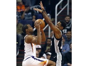 Phoenix Suns forward TJ Warren shoots over the San Antonio Spurs guard DeMar DeRozan, right, during the first half of an NBA basketball game, Wednesday, Nov. 14, 2018, in Phoenix.