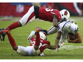 Arizona Cardinals outside linebacker Haason Reddick, top, and cornerback Jamar Taylor tackle Oakland Raiders wide receiver Marcell Ateman (88) during the first half of an NFL football game, Sunday, Nov. 18, 2018, in Glendale, Ariz.