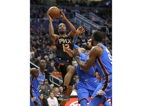 Phoenix Suns forward TJ Warren (12) drives between Oklahoma City Thunder's Steven Adams and Patrick Patterson (54) during the first half of an NBA basketball game Saturday, Nov. 17, 2018, in Phoenix.