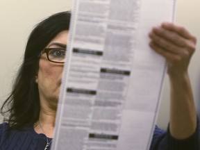 An elections worker examines a ballot before inserting it into a counting machine at Pima County Elections in Tucson, Ariz., Monday, Nov. 12, 2018.