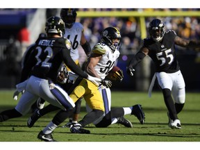 Pittsburgh Steelers running back James Conner, center, rushes the ball past Baltimore Ravens free safety Eric Weddle (32) and outside linebacker Terrell Suggs (55) in the first half of an NFL football game, Sunday, Nov. 4, 2018, in Baltimore.