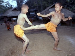 FILE - In this March 19, 2002, file photo, two novice Buddhist monks practice Muay Thai (Thai kickboxing) during a morning training session at the Golden Horse Monastery in northern Thailand. The death of a 13-year-old boy who was knocked out during a Muay Thai boxing match in Thailand has sparked debate over whether to ban child boxing.
