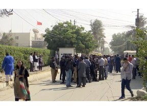In this image made from video, security officials gather outside the compound of the Chinese Consulate following an attack, Friday, Nov. 23, 2018, in Karachi, Pakistan. Gunmen have stormed the Chinese Consulate in Pakistan's southern port city of Karachi, triggering an intense shootout during which two police officers and all three assailants were killed. (AP Photo)