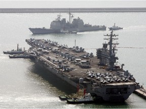 FILE - In this March 22, 2007, file photo, the U.S. aircraft carrier USS Ronald Reagan, bottom, anchors as U.S. Aegis Ship passes after they arrive at Busan port for joint military exercises in Busan, South Korea. China is allowing a U.S. Navy aircraft carrier and its battle group to make a port call in Hong Kong after it turned down similar request amid tensions with Washington. The Marine Department's website listed the USS Ronald Reagan and three other Navy warships as approved to arrive on Wednesday.