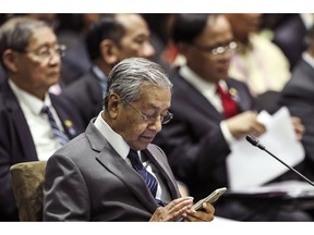 Malaysian Prime Minister Mahathir Mohamad uses his mobile phone during the 13th East Asian Summit Plenary on the sidelines of the 33rd ASEAN summit in Singapore, Thursday, Nov. 15, 2018. At 93, Malaysia's comeback prime minister, Mahathir Mohamed, cuts a striking figure as the center of attention at a Southeast Asian summit in Singapore.