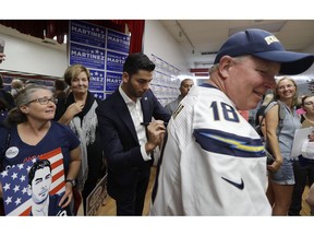 Democratic congressional candidate Ammar Campa-Najjar, center, signs a Los Angeles Chargers football jersey worn by Dan Steussy Monday, Nov. 5, 2018, in Escondido, Calif. Campa-Najjar faces indicted U.S. Rep. Duncan Hunter in the race for Southern California's 50th district.